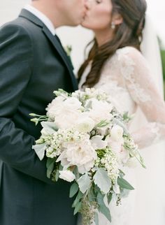 a bride and groom kissing in front of a building