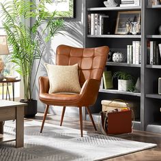 a brown chair sitting in front of a book shelf filled with books and other items