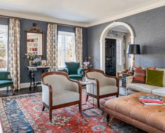 a living room filled with lots of furniture next to two windows and a rug on the floor