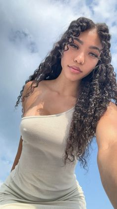 a woman with long curly hair posing for the camera