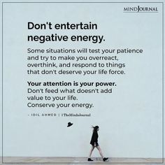 a woman walking past a white wall with the words don't entertain negative energy