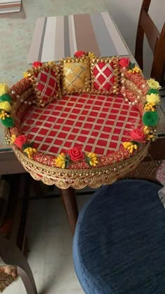 a red and gold tray sitting on top of a table next to a blue chair