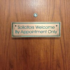 a sign that is on the side of a door saying, solicitors welcome by appointment only