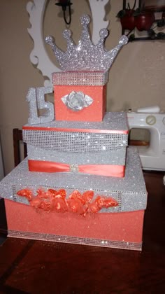 a three tiered cake with a crown on top and ribbons around the edges, sitting on a table