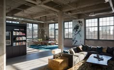 a living room filled with lots of furniture next to large windows and a book shelf