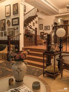 a living room filled with lots of furniture and pictures on the wall next to stairs