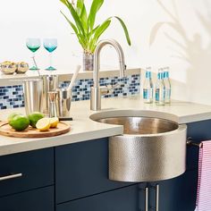 a kitchen with blue cabinets and white countertops has a stainless steel sink in the center