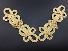 a gold necklace on a black surface with an intricate knot around the neck and two circular links