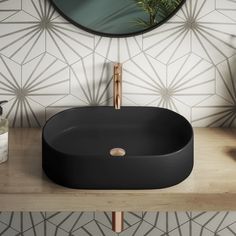 a black sink sitting on top of a wooden counter next to a mirror and plant