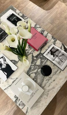 a marble coffee table topped with books and flowers