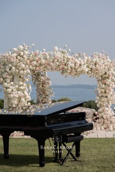 a grand piano sitting in front of a floral arch with white and pink flowers on it