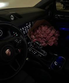 a bouquet of roses sits in the center console of a car, next to a steering wheel