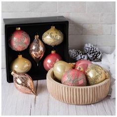 a bowl filled with christmas ornaments next to a black box