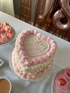 a heart shaped cake sitting on top of a table next to other desserts and drinks