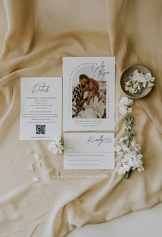 the wedding stationery is laid out on top of the bed with flowers in front of it