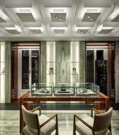 two chairs sitting in front of a table with glass cases on it and lights hanging from the ceiling