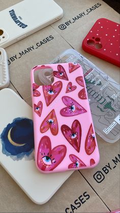 pink phone case with hearts on it sitting next to other cell phones and cases for sale