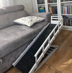 a couch that is sitting in front of a book shelf with a pillow on it