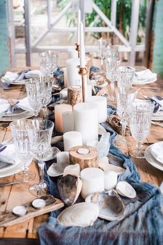 the table is set with white dishes and silverware, candles and napkins on it