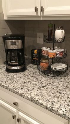 a kitchen counter with coffee maker, mugs and other items on top of it