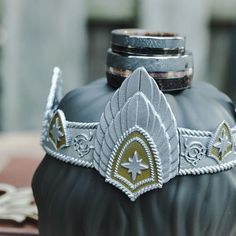 a crown is sitting on top of a black vase with gold trimmings and silver accents