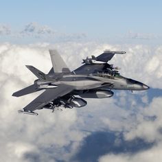 a fighter jet flying through the sky above clouds