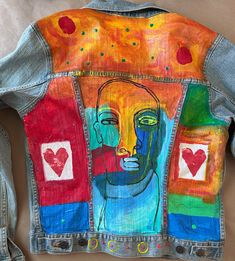 a jean jacket with an image of a woman's face painted on the back