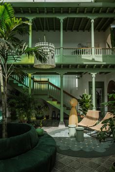 an indoor area with green furniture and plants in the foreground, stairs leading up to second floor