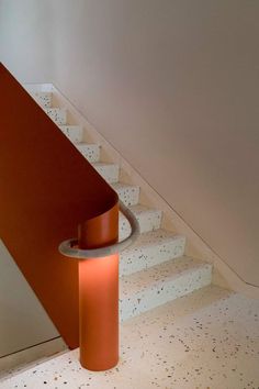 an orange lamp sitting on the side of a stair case next to a set of stairs