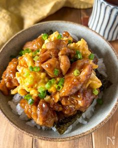 a bowl filled with rice and meat on top of a wooden table