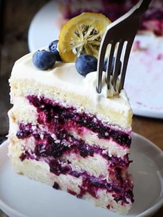 a slice of cake with blueberries and lemon on top is being held by a fork