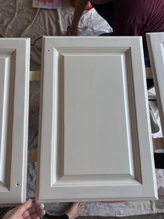 two people are working on some white cabinet doors