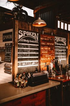 a bar with menus on the wall and lights hanging from it's ceiling