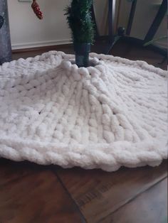 a white blanket sitting on top of a wooden floor next to a potted plant