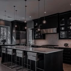 a large kitchen with black cabinets and marble counter tops, an island in the middle