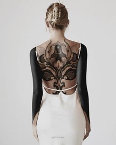 the back of a woman's dress with black and white designs on her body