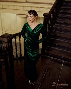 a woman in a green dress is standing on the stairs