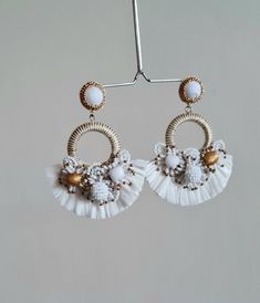 "Boho Handmade Raffia embellished white and gold wedding hoop earring. These boho wedding earrings are one of the most beautiful and one of the rare workmanship on any handmade earrings. The hoop earrings are made of multiple elements like tiny seed beads of white, gold, and fringes of raffia. The tiny seed bead balls and flowers are made with patience and aligned to make them look great for Wedding Jewellery. The gold color is used as an accent. The Earrings measure about approx. 3.10\" long an White Round Hoop Earrings For Festival, Handmade Delicate Pearl White Bridal Earrings, Delicate Handmade Pearl White Bridal Earrings, Beaded Hoop Earrings For Wedding, White Beaded Hoop Earrings For Wedding, Adjustable Beaded Earrings For Wedding, Handmade Pearl White Bridal Earrings For Wedding, Handmade Adjustable Pearl White Earrings, Handmade Elegant Hoop Chandelier Earrings