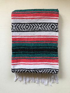 a red, green and white blanket with fringes