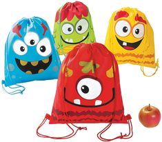 three drawstring bags with cartoon faces on them and an apple in the background