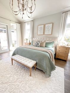 a bedroom with a large bed, chandelier and white rug on the floor