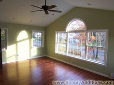 an empty living room with wood floors and large windows in the middle of the room