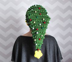 a woman wearing a green crocheted hat with pom poms on it