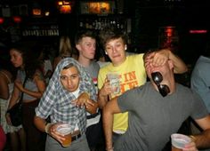 a group of young men standing around each other at a bar with drinks in their hands