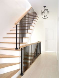 a staircase with wooden handrails next to a white door and light hanging from the ceiling