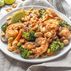 a white plate topped with pasta and broccoli next to a lime wedge on top of a cloth