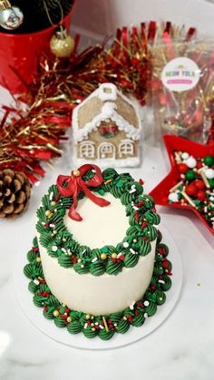 a decorated christmas cake sitting on top of a white table next to other holiday decorations