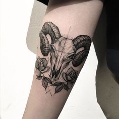 a ram tattoo on the arm with roses and leaves around its head, in black and white