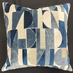 a blue and white pillow with an abstract design on the front, sitting on a black background