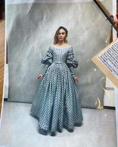 a woman in a polka dot dress is standing next to a large sheet of paper